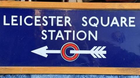 Blue vintage Leicester Square Station sign with direction arrow under the text