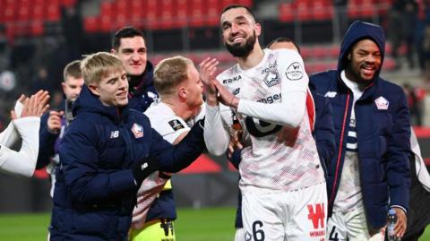 A smiling Nabil Bentaleb celebrating with his Lille team-mates at full time.