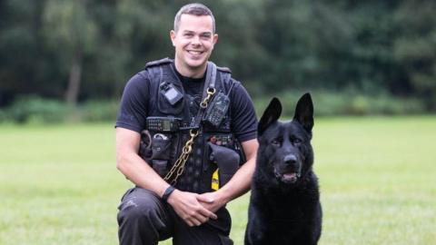 PC Chris Duffy kneels next to a police dog