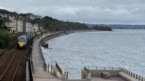 Dawlish - houses, a train, a sea wall and the sea on a stormy day