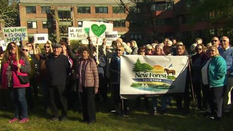 Crowds of people stood with signs outside the New Forest District Council offices.