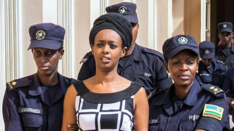 Diane Rwigara (C), a prominent critic of Rwanda's President Paul Kagame, is escorted by Police officers to the court room at the Nyarugenge intermediate court in Kigali on October 9, 2017