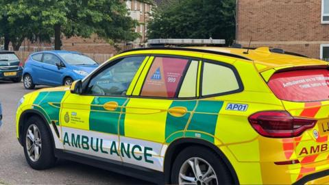 An East Midlands Ambulance Service fast response vehicle parked on a road outside a block of flats
