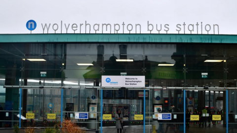 The main sign for the station can be seen above the glass door entrance to the station. It reads "Wolverhampton Bus Station" and a smaller sign just over the glass sliding door says "Welcome to Wolverhampton Bus Station".