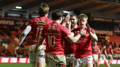 Ellis Mee celebrates scoring a try with Scarlets team mates