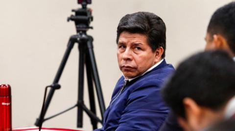 Pedro Castillo, wearing a blue jacket, has a serious expression as he is handed his sentence handed down by the court that tried him for the failed coup attempt in 2022.