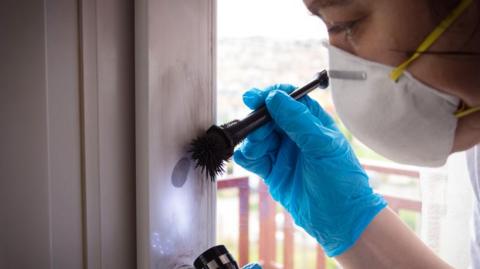 Image of a forensic scientist dusting for fingerprints