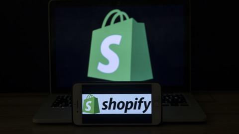 Shopify logo on mobile phone and laptop.
