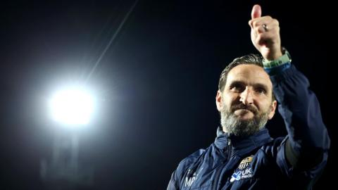 Notts County boss Martin Paterson gives his a thumbs up while stood in front of flood lights