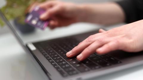 A picture of someone inputting card details into a computer.