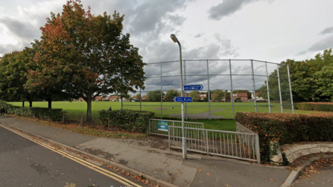 A Google street view of and entrance to Victoria Park in Taunton. It appears to be a mostly flat field with trees around the outside.