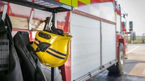 A yellow helmet hanging from a hook on a fire engine