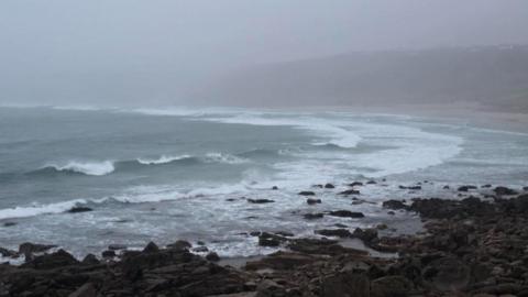 Rough waves at Sennen Cove in Cornwall with a grey sky and now people about.