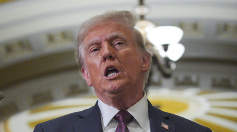 U.S. President-elect Donald Trump speaking in a navy suit, white shirt and navy and red spotted tie