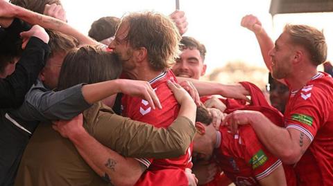 York City players in red kit celebrate with players