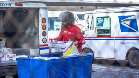 A United States Postal Service (USPS) worker in a red shirt loads a mail car in Miami, Florida, USA, 05 February 2025. 