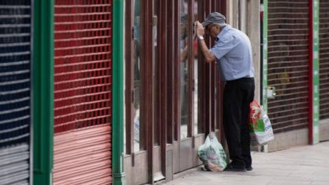 A man looks into the window of a closed coffee shop in Cardiff