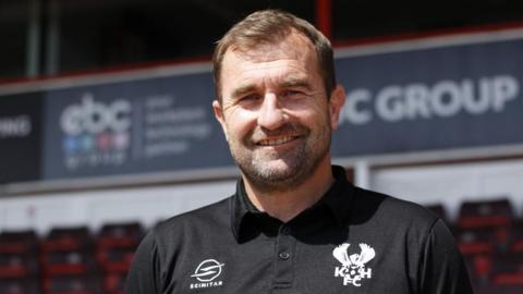 Kidderminster Harriers manager Paul Wotton is wearing his black club polo shirt.
