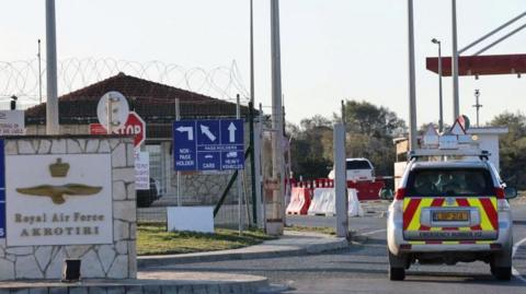 Entrance to RAF Akrotiri with an emergency vehicle next to a sign with the base's name