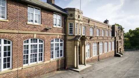 The front of a brick-built building stretches off into the distance 