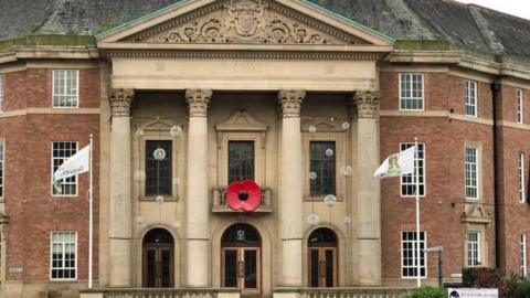 Front view of Derby City Council headquarters, a three-storey brick building, with a large poppy attached to a balcony