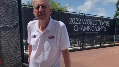 Man standing infront of 2022 world tennis championships sign wearing white t shirt