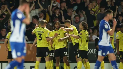 Burton players and fans celebrate Rumarn Burrell's goal against Wigan