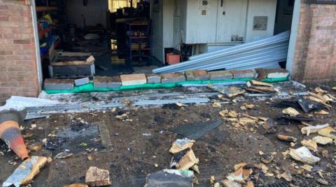 Rubble is on the ground outside a brick building.