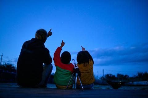 Silhouette of father and children pointing to sky