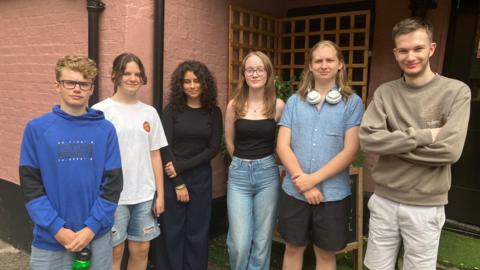 A picture of six young people standing in a row outside a building in Berkhamsted. Three of them are boys and three of them are girls.