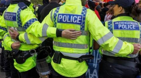 Rear view of Greater Manchester Police officers with arms linked during protests