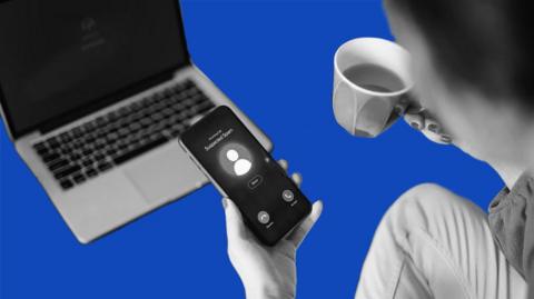 Woman gets a suspected scam call on her phone while drinking a cup of tea