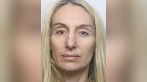 A custody mugshot of a woman with long blonde hair