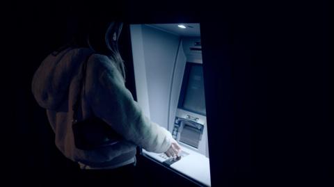 Stock photo of a person at a cash machine in the dark 