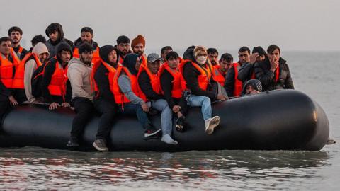  Migrants sit on a dinghy as they prepare to sail into the English Channel 