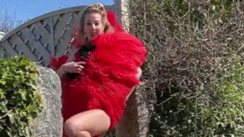 A woman holding a large red boa in a street.