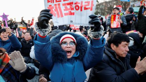 People in South Korea celebrate after parliament passes a motion to impeach President Yoon Suk Yeol