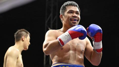 Manny Pacquiao smiles in the ring with his gloves up