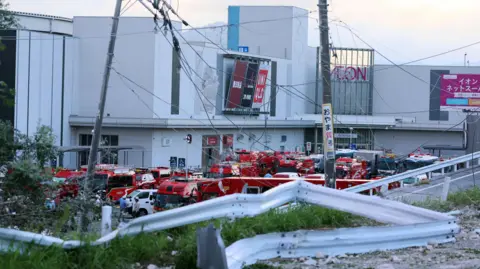 Red fire trucks in front of an Aeon Mall in Kumamoto Japan that was damaged by a powerful earthquake
