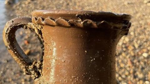 Image of Malcolm Russell's hand holding the brown sculpted drinking vessel.