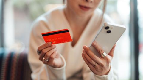 Woman holding red credit card and mobile phone