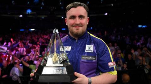 Luke Littler poses with the Premier League trophy