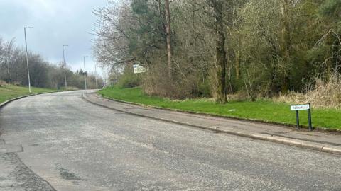 A road, curving to the right with a sign saying Earnhill Road