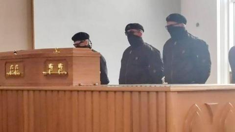 An image appearing to show masked men at a funeral at Roselawn Crematorium in April