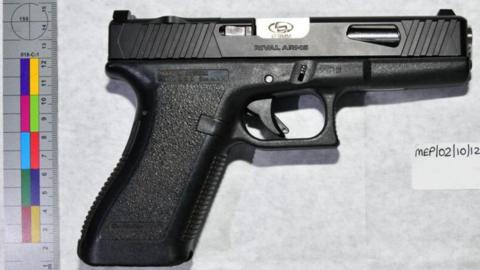 One of the four recovered Glock pistols during the NCA house raid. It is black. It is laid on a table next to rules showing it is about 12cm in size.