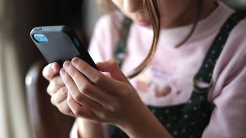 Stock image showing a close-up of a young girl's hands holding a smart phone