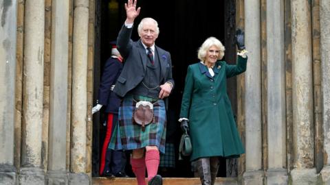 Britain's King Charles III, wearing a kilt, and Britain's Camilla, Queen Consort wave as they walk to meet members of the public after leaving from Dunfermline Abbey in Dunfermline in south east Scotland on October 3, 2022.