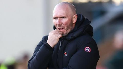 Shrewsbury Town manager Michael Appleton watches on from the touchline in his club puffer coat