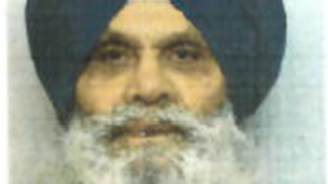 A blurry mugshot photo of Singh Mauji. He is wearing a black turban and has a bushy grey beard and moustache