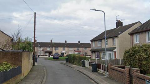 A small cul de sac of semi detached houses with a green area in the middle.